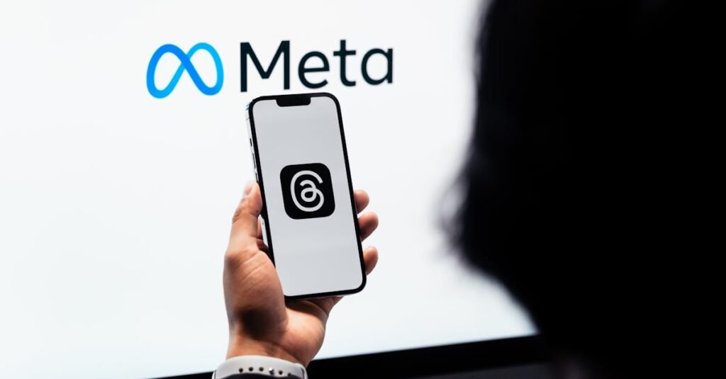 Hands holding smartphone with Meta Threads logo on screen, Meta branding in background.